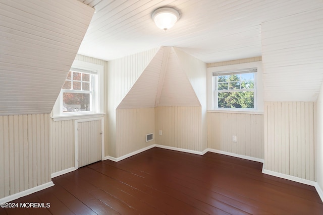 additional living space featuring wood-type flooring, visible vents, vaulted ceiling, and baseboards