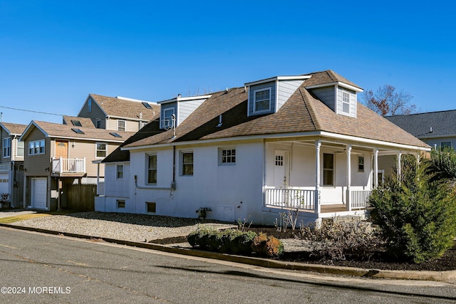 view of front of home featuring a shingled roof, covered porch, and stucco siding