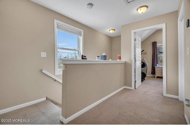 hall featuring carpet flooring, baseboards, and an upstairs landing