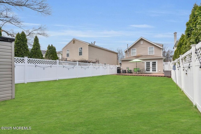 rear view of house with french doors, a fenced backyard, and a yard