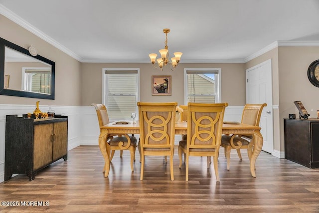 dining room featuring crown molding, wainscoting, wood finished floors, and a notable chandelier