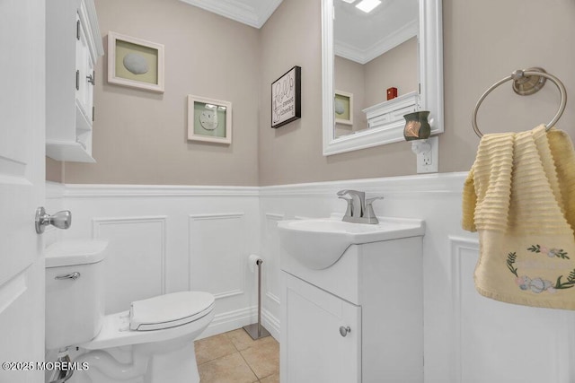 half bath with a wainscoted wall, toilet, ornamental molding, vanity, and tile patterned floors