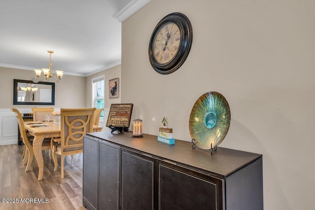 dining room featuring a notable chandelier, ornamental molding, and wood finished floors