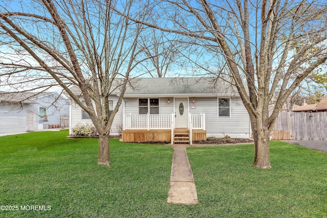 ranch-style house featuring a shingled roof, fence, and a front lawn