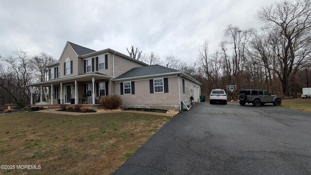 view of front of property featuring a porch, a front yard, and aphalt driveway