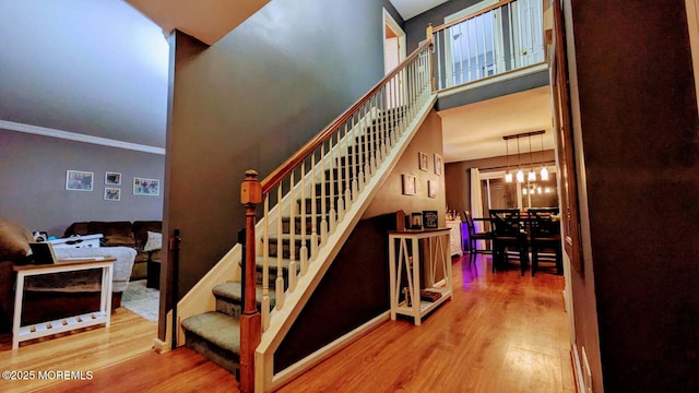 staircase with an inviting chandelier, a high ceiling, and wood finished floors