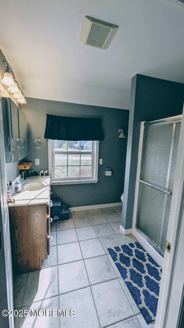 full bathroom featuring vanity, a stall shower, tile patterned floors, toilet, and visible vents