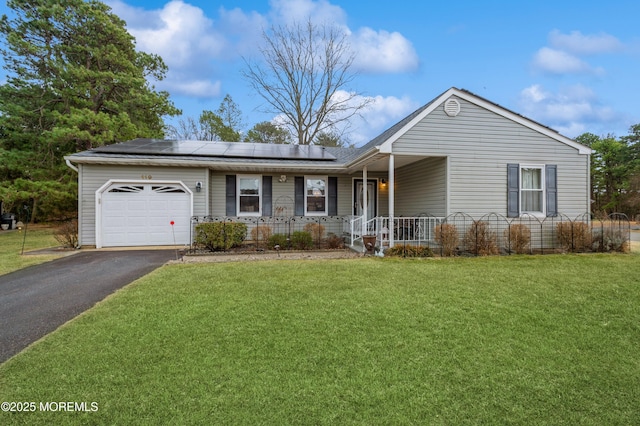 single story home featuring driveway, solar panels, an attached garage, covered porch, and a front lawn