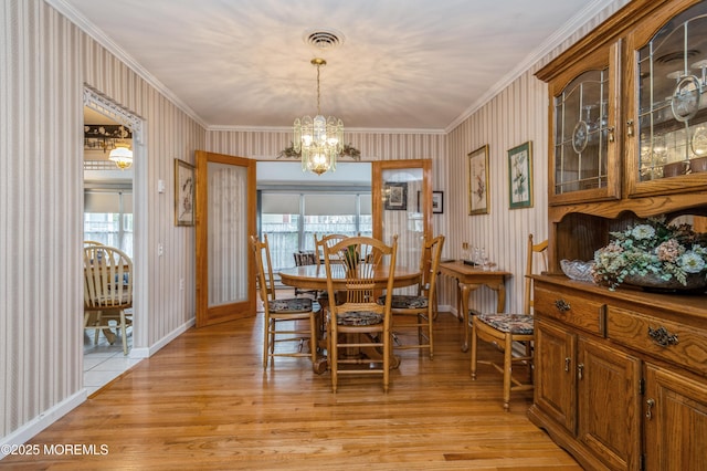 dining room featuring crown molding, baseboards, visible vents, and light wood-style floors