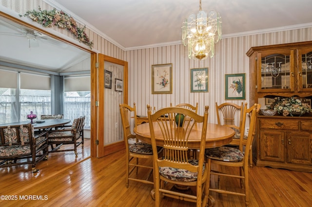 dining area with crown molding, ceiling fan with notable chandelier, light wood-style flooring, and wallpapered walls