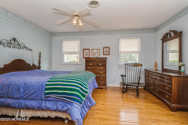 bedroom with light wood-type flooring, wallpapered walls, multiple windows, and visible vents