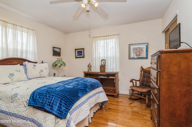 bedroom with light wood-style floors, multiple windows, baseboards, and a ceiling fan