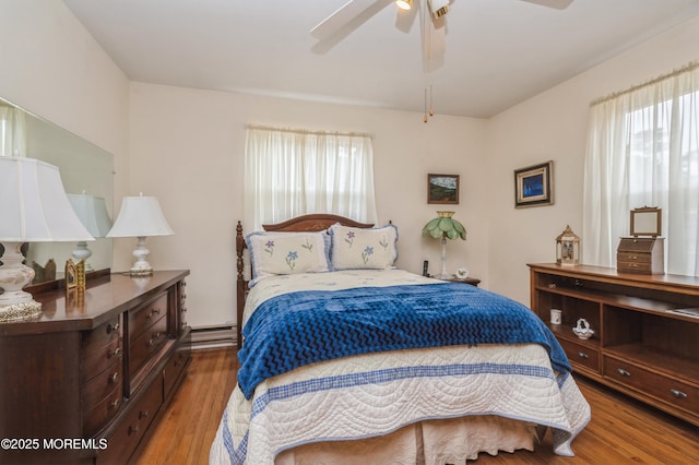 bedroom featuring a baseboard radiator, wood finished floors, and a ceiling fan