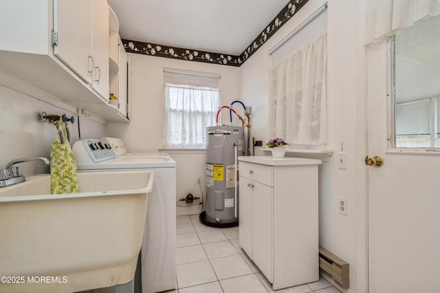 clothes washing area featuring light tile patterned floors, electric water heater, a sink, cabinet space, and washing machine and clothes dryer