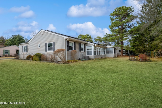 exterior space featuring central air condition unit, a sunroom, and a lawn