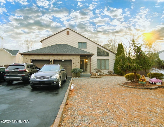 mid-century inspired home with a garage, brick siding, driveway, and a shingled roof