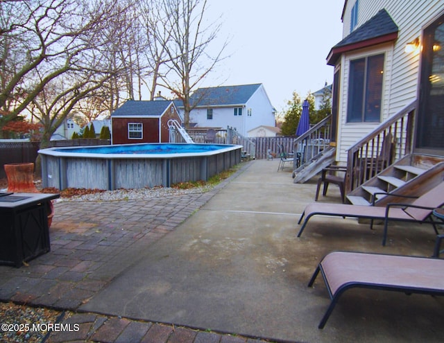 view of patio with a fenced in pool, an outbuilding, entry steps, a shed, and a fenced backyard