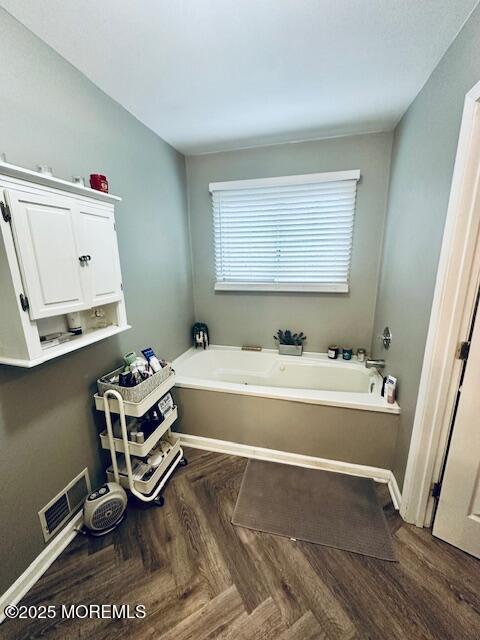 bathroom with a garden tub, visible vents, and baseboards