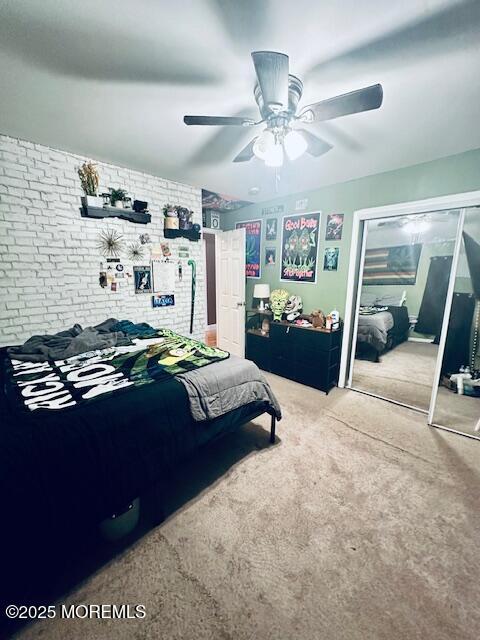 carpeted bedroom with ceiling fan and brick wall