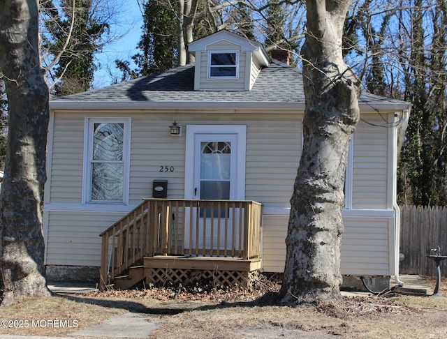 view of front of home featuring roof with shingles and fence