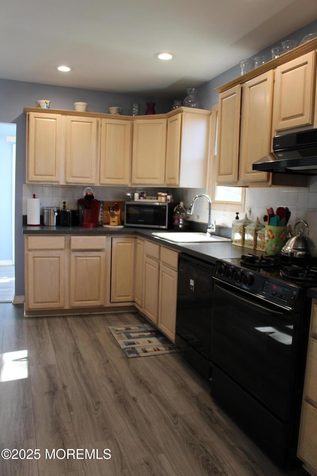 kitchen featuring wood finished floors, under cabinet range hood, black appliances, light brown cabinets, and a sink