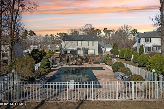 back of property at dusk with a residential view, a fenced in pool, a patio, and fence