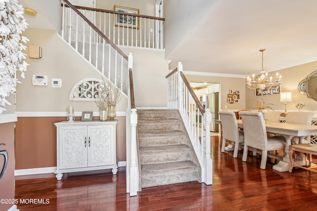 stairway featuring a notable chandelier, crown molding, baseboards, and wood finished floors