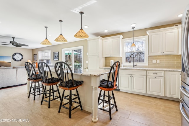 kitchen with a sink, a breakfast bar, open floor plan, and white cabinets