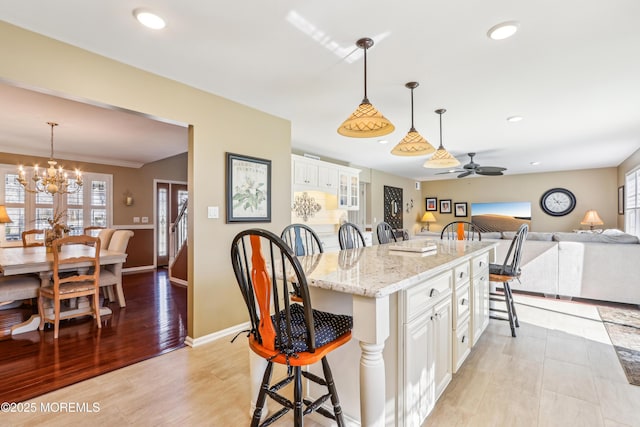 kitchen with pendant lighting, a kitchen breakfast bar, white cabinetry, recessed lighting, and light stone countertops