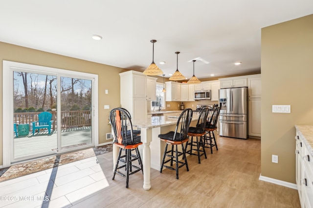 kitchen featuring light stone counters, stainless steel appliances, a kitchen breakfast bar, and a center island