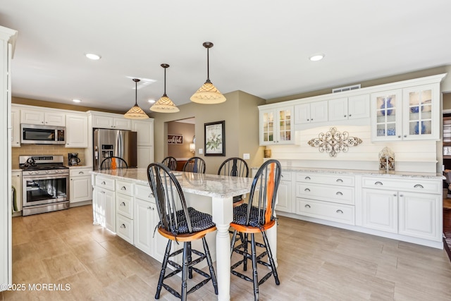 kitchen featuring tasteful backsplash, visible vents, appliances with stainless steel finishes, and a kitchen breakfast bar