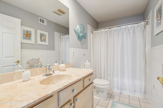 bathroom featuring tile patterned flooring, visible vents, toilet, vanity, and tile walls