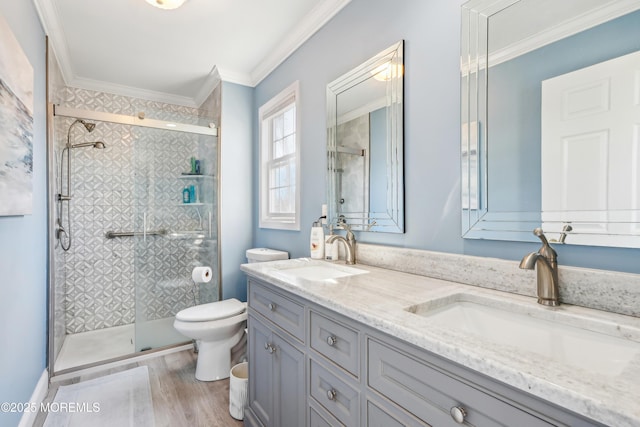 bathroom featuring ornamental molding, toilet, a shower stall, and a sink