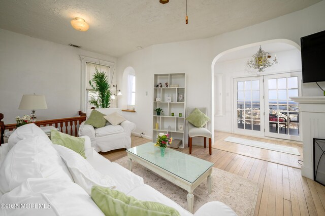 75 Highland Ave, Highlands, NJ 07732 - living area with visible vents, arched walkways, wood-type flooring, a textured ceiling, and a notable chandelier