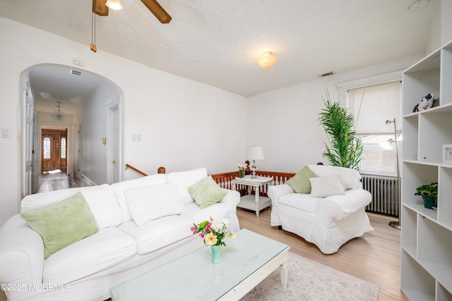 75 Highland Ave, Highlands, NJ 07732 - living area featuring visible vents, a ceiling fan, arched walkways, radiator, and light wood finished floors