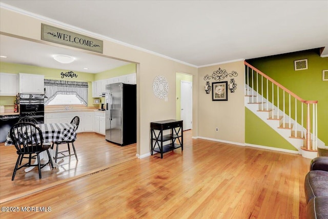 dining room with baseboards, visible vents, light wood-style flooring, stairs, and crown molding