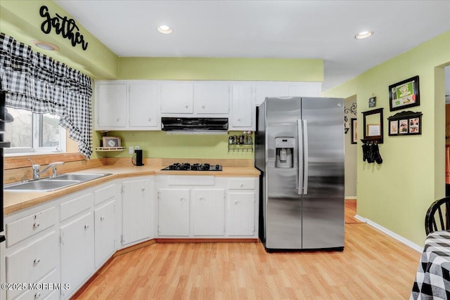 kitchen featuring stainless steel fridge with ice dispenser, light countertops, extractor fan, light wood-type flooring, and a sink