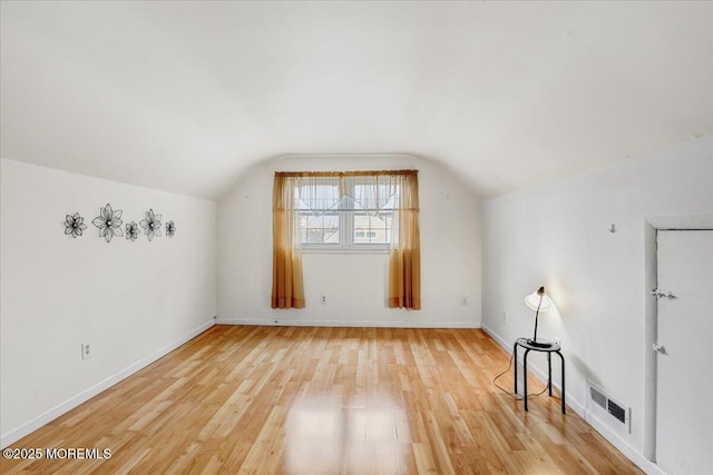 bonus room with lofted ceiling, baseboards, visible vents, and light wood-style floors