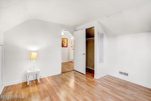 interior space featuring lofted ceiling, light wood-style flooring, visible vents, baseboards, and a closet