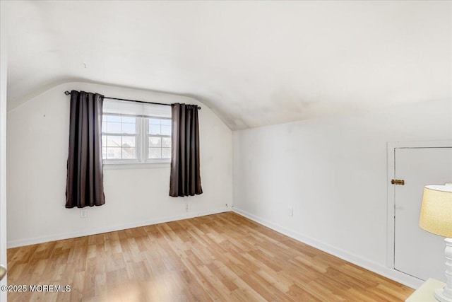 additional living space featuring light wood-style floors, lofted ceiling, and baseboards