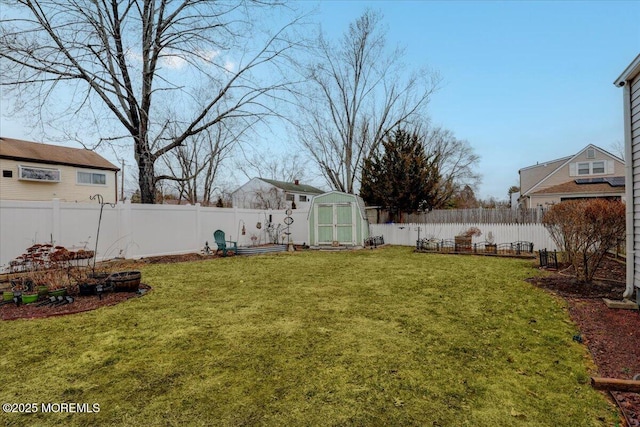 view of yard with a storage shed, a fenced backyard, and an outdoor structure