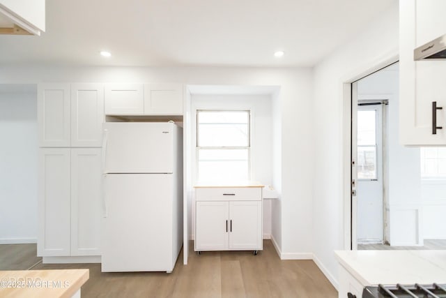 kitchen with light wood-style flooring, recessed lighting, white cabinets, light countertops, and freestanding refrigerator