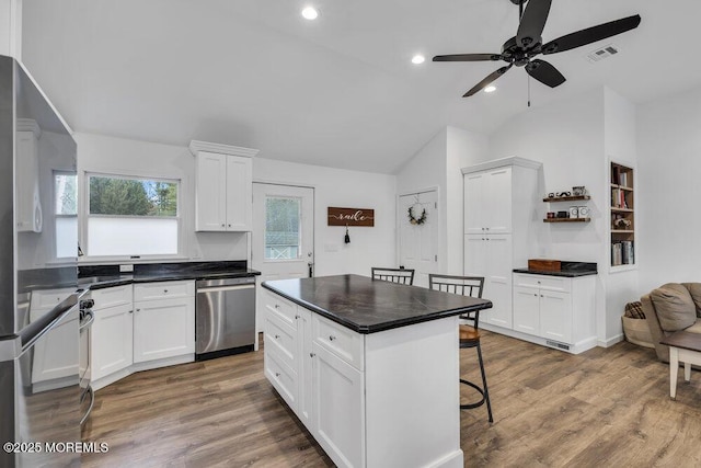 kitchen featuring visible vents, white cabinets, wood finished floors, and stainless steel dishwasher