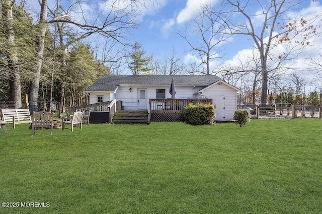 rear view of property featuring fence, a lawn, and a wooden deck