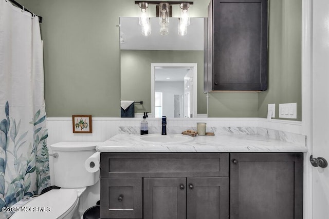 full bathroom with vanity, toilet, and wainscoting