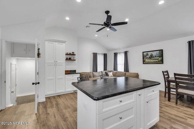 kitchen featuring white cabinetry, lofted ceiling, wood finished floors, and dark countertops