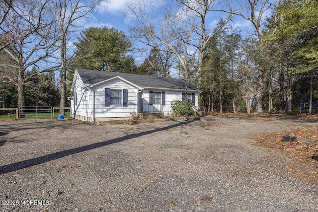 view of front of home featuring driveway, roof with shingles, and fence