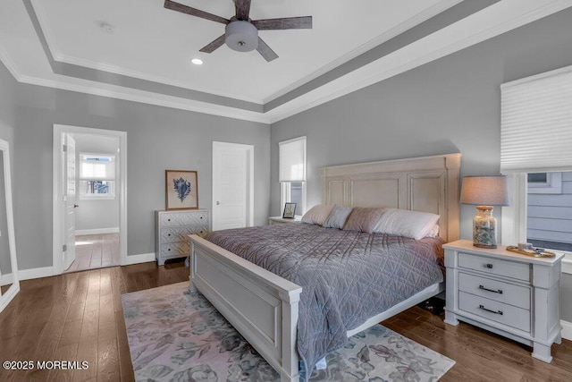 bedroom featuring baseboards, a tray ceiling, dark wood-style flooring, ceiling fan, and crown molding