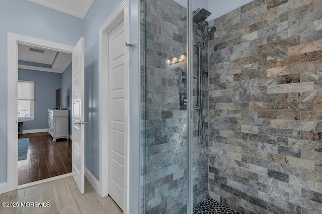 full bathroom with a stall shower, wood finished floors, baseboards, and ornamental molding