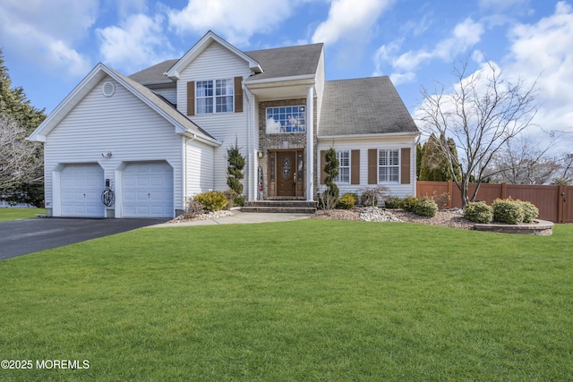 traditional-style home with an attached garage, fence, driveway, and a front lawn